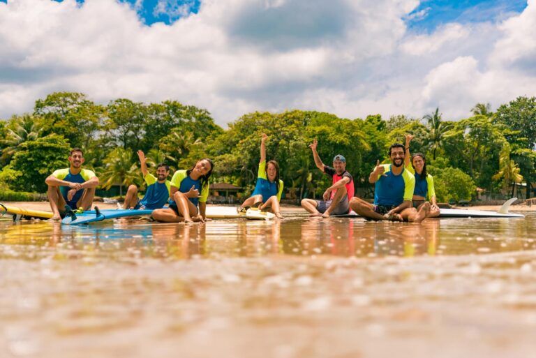 Grupo de alumnos de surf al borde del agua en Tamarindo