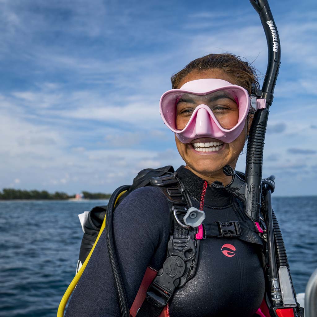 diver with a pink mask on a boat making a big smile