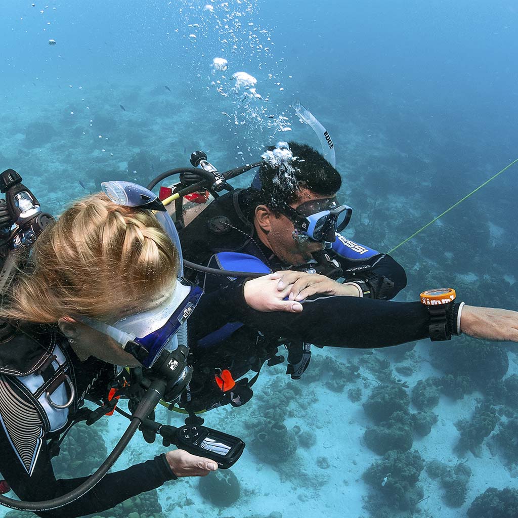 two divers practicing underwater navigation in the ocean